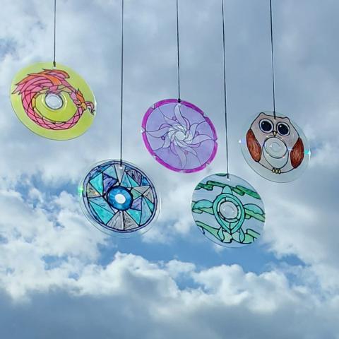 Five circular suncatchers hanging in a sunny window.